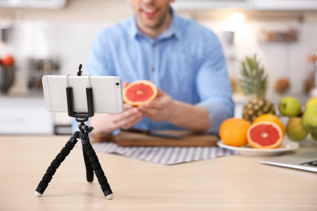 Young blogger with fruits recording video on kitchenの写真素材