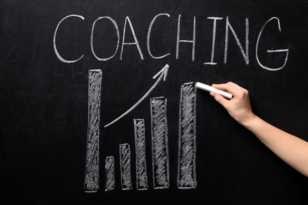 Woman drawing bar chart with word COACHING on chalkboard. business trainer conceptの写真素材
