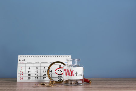 Calendar, glass jar with label "TAX TIME" and coins on tableの写真素材