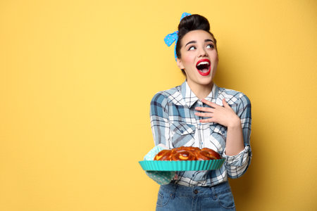 Funny young housewife with homemade pastry on color background