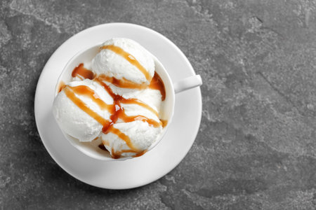 Tasty ice cream with caramel sauce in mug on gray background, top viewの写真素材