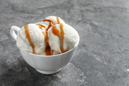 Tasty ice cream with caramel sauce in mug on tableの写真素材