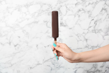 Woman holding yummy ice cream on marble background. focus on handの写真素材