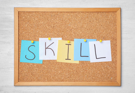Notes with word SKILL pinned to cork board on wooden background. business trainer conceptの写真素材