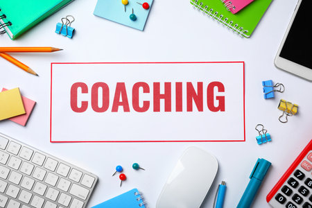Word COACHING, mobile phone, keyboard and office stationery on white background. business trainer conceptの写真素材