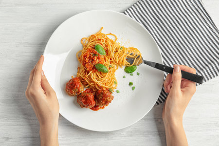 Woman having pasta with meatballs and tomato sauce at table, closeupの写真素材