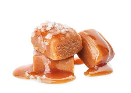 Delicious candies with caramel sauce and salt on white backgroundの写真素材