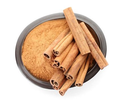 Bowl with aromatic cinnamon sticks and powder on white backgroundの写真素材
