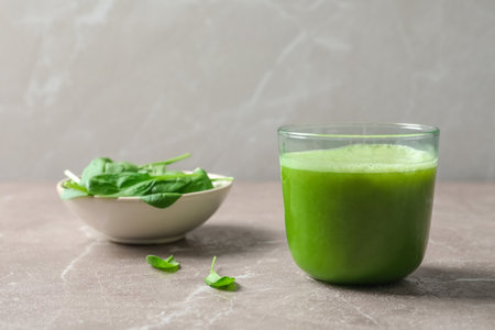 Glass with delicious detox juice and spinach on tableの写真素材