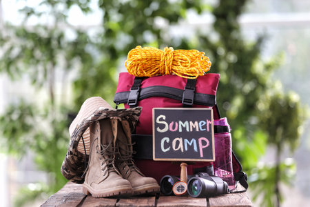 Composition with backpack and camping equipment on table against blurred backgroundの写真素材