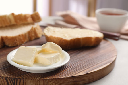 Plate with tasty butter and fresh bread on wooden boardの写真素材