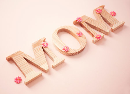Word MOM made of wooden letters and flowers on light background. mother's day congratulationsの写真素材