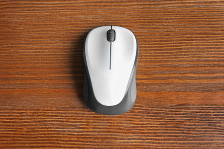 Wireless computer mouse on wooden background, top view
