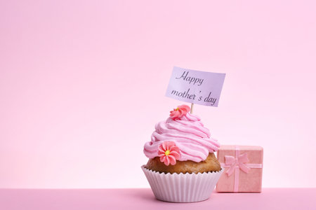 Tasty cupcake and gift box for Mother's Day on color backgroundの写真素材
