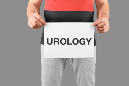 Mature man holding paper with word UROLOGY on gray backgroundの写真素材