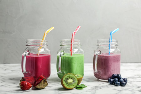 Mason jars with healthy detox smoothies and ingredients on tableの写真素材