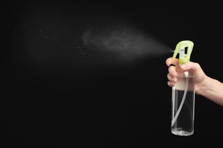 Woman spraying air freshener on black background, closeupの写真素材