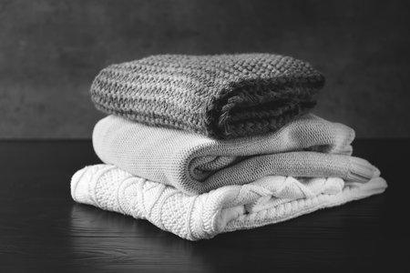 Stack of warm knitted clothes on tableの写真素材