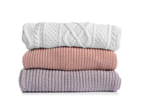 Stack of warm knitted clothes on white backgroundの写真素材