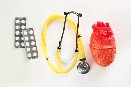 Stethoscope, pills and model of heart on light background. heart attack conceptの写真素材