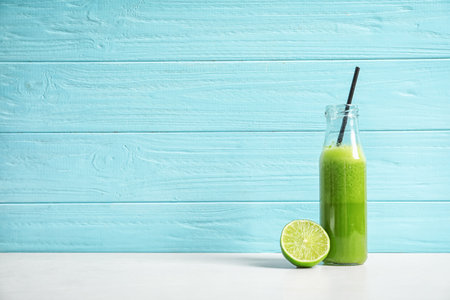 Bottle with delicious detox juice and lime on table
