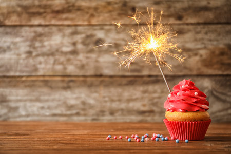 Delicious birthday cupcake with sparkler on tableの写真素材