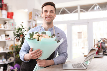 Male florist holding bouquet flowers at workplaceの写真素材
