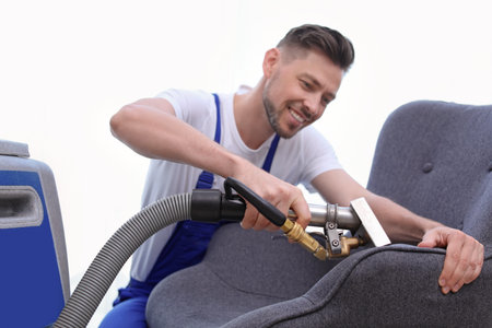 Dry cleaning worker removing dirt from armchair indoorsの写真素材
