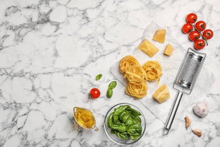 Beautiful composition with raw pasta and ingredients for sauce on marble background, top viewの写真素材