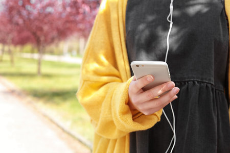Young woman using phone for listening to music outdoorsの写真素材