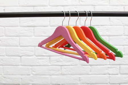 Clothes hangers on metal rail against brick wall backgroundの写真素材