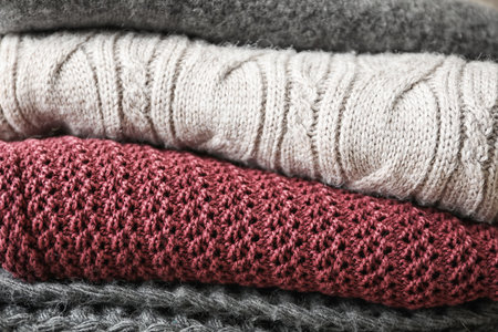 Stack of warm knitted clothes as background