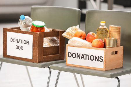 Donation boxes with food products on chairs indoorsの写真素材