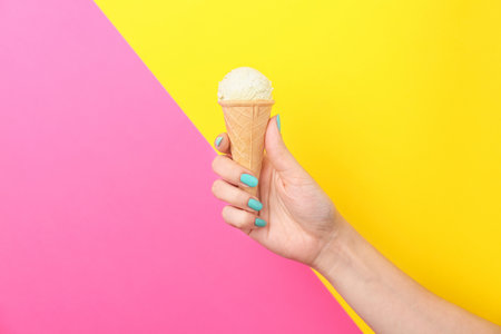 Woman holding yummy ice cream on color background. focus on handの写真素材