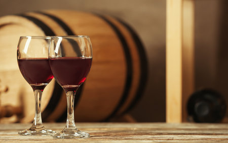 Glasses with red wine and blurred barrel on backgroundの写真素材