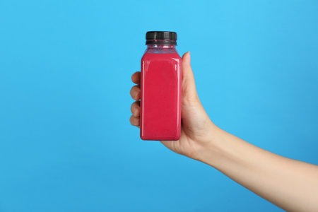 Woman holding bottle with delicious smoothie on color backgroundの写真素材