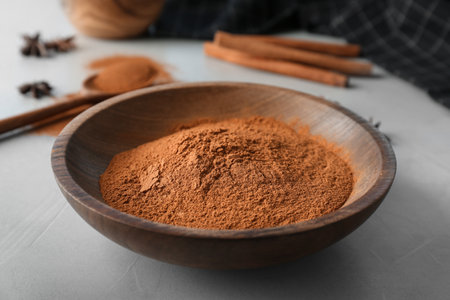 Bowl with aromatic cinnamon powder on tableの写真素材