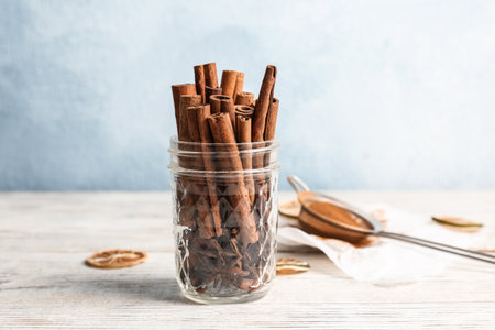 Jar with aromatic cinnamon sticks on wooden table