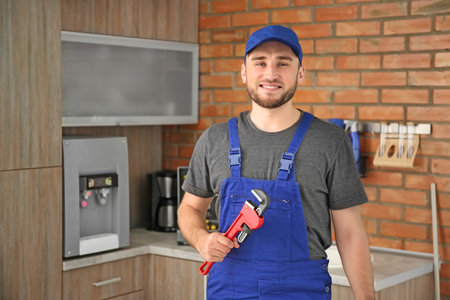Professional plumber in uniform with pipe wrench indoorsの写真素材