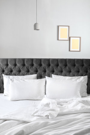Comfortable bed with white linen and pillows at homeの写真素材