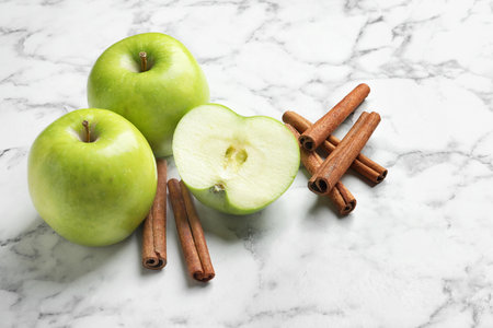 Fresh apples and cinnamon sticks on marble tableの写真素材