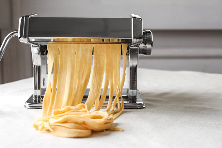 Pasta maker with wheat dough on tableの写真素材