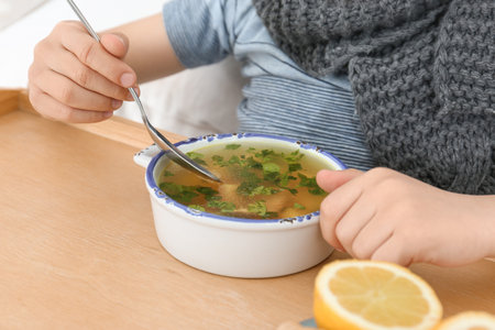 Sick little boy eating broth to cure cold, closeupの写真素材