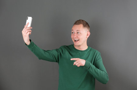 Handsome man taking selfie on color backgroundの写真素材
