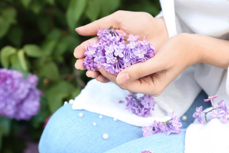 Young woman with blossoming lilac outdoors on spring dayの写真素材