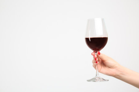 Woman holding glass of red wine on white backgroundの写真素材