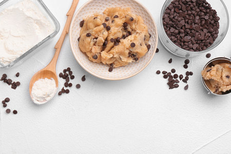Flat lay composition with cookie dough, chocolate chips and flour on light backgroundの写真素材