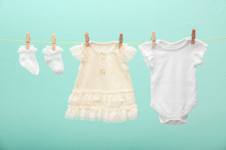 Children's clothes on laundry line against color backgroundの写真素材