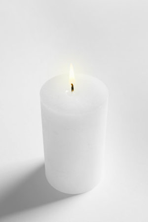 Pillar wax candle burning on white backgroundの写真素材