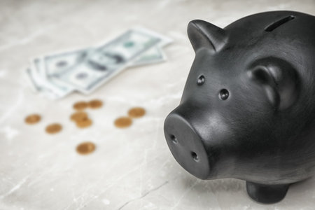 Black piggy bank and money on tableの写真素材